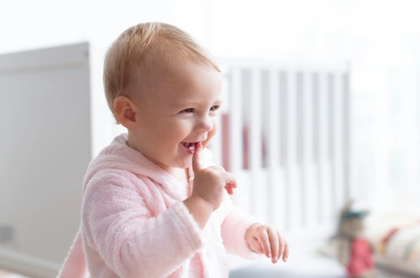 niedliches Baby, das in ihrem Kinderzimmer lächelt