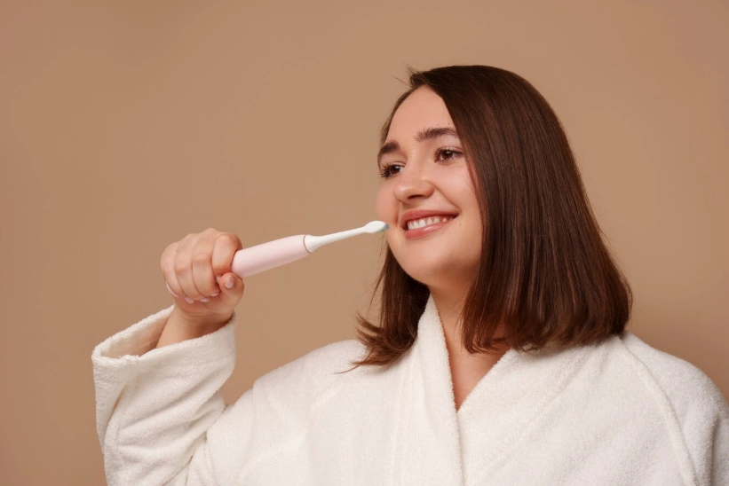 femme se brossant les dents avec une brosse à dents électrique
